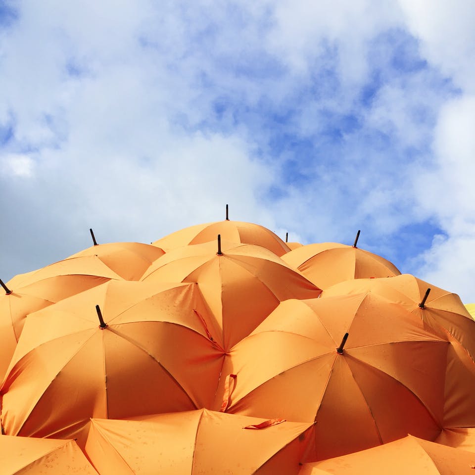 Viele orangenfarbene Sonnenschirme unter blauem Himmel