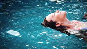 Frau schwebt im Pool mit geschlossenen Augen