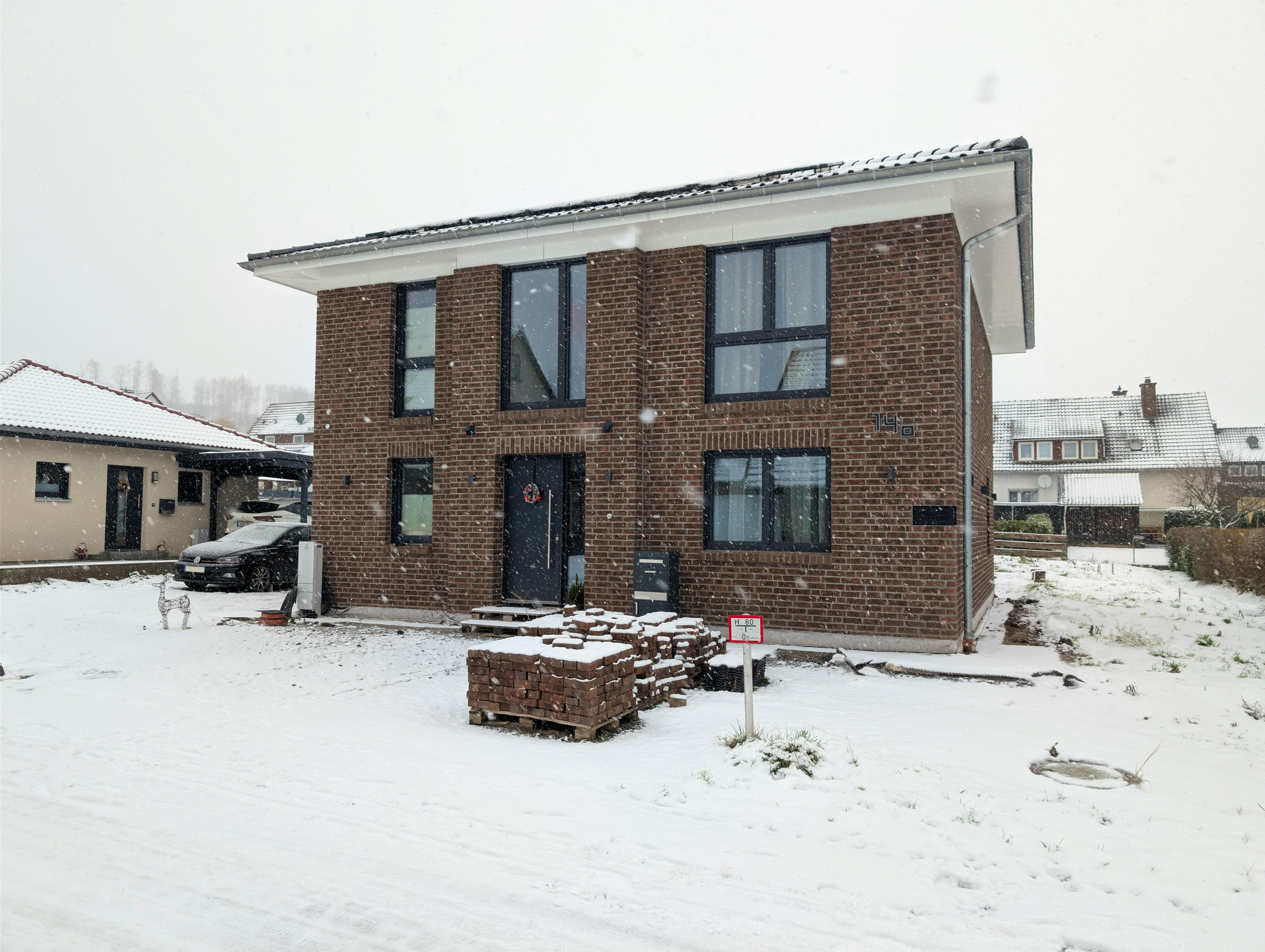 Viebrockhaus-Stadtvilla in Bodenfelde im Winter bei Schneefall – Klinkerfassade, Weihnachtskranz an der Tür, LED-Rentier im Vorgarten