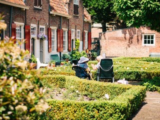 Altes Ehepaar sitzt im Garten vor eigenem Haus