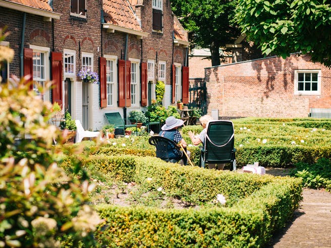 Altes Ehepaar sitzt im Garten vor eigenem Haus