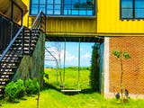 Gelbes Containerhaus mit Treppe und Schaukel