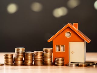 Symbolbild Haus und Geldmünzen