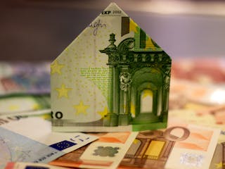 Geldscheine und gefaltetes Haus aus Geldschein