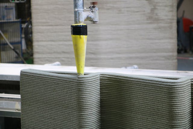 Die am Druckerarm befestigte Düse spritzt für ein 3D-gedrucktes Haus Betonlinien exakt aufeinander