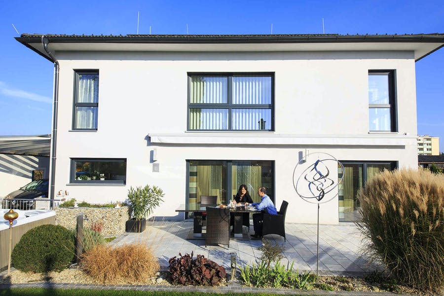 Paar sitzt vor seinem weißen VARIO-HAUS auf der Terrasse