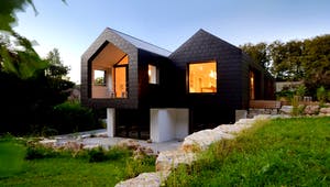 Ein schwarz verkleidetes Architektenhaus mit doppeltem Satteldach