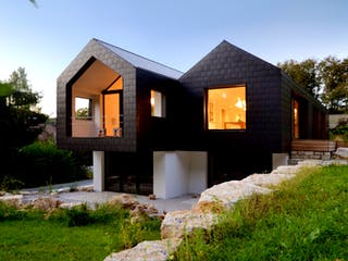 Ein schwarz verkleidetes Architektenhaus mit doppeltem Satteldach