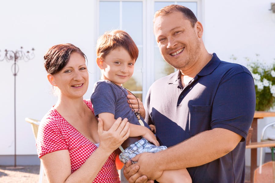 Vater, Mutter und Kind vor ihrem neuen Haus von Schwörer