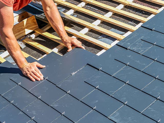 Handwerker deckt Schieferdach in Rechteck-Deckung